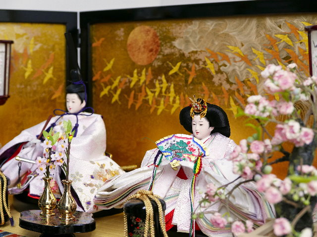 淡い薄ピンクの雛人形を鶴の金屏風と黒塗り台に並べる収納飾り