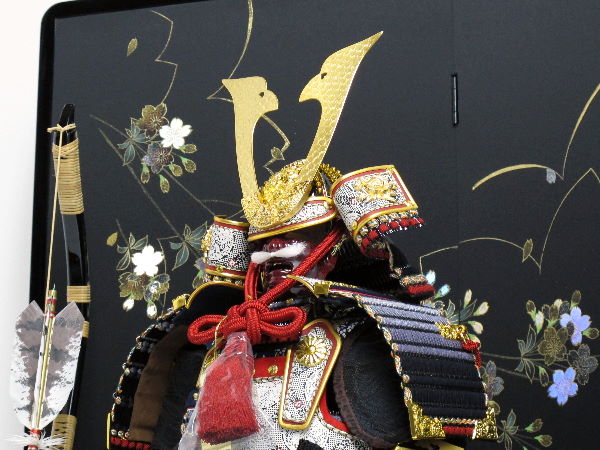 黒い小札を黒糸で威した渋めのコンパクト大鎧を桜の黒屏風で飾る五月人形
