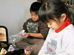 女の子と男の子が二人で雛人形の飾りつけを楽しんでいます。