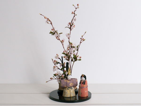 玄関飾りにもなるコンパクトな立雛に梅をつけて華やかに飾りました。柿沼東光の立雛です