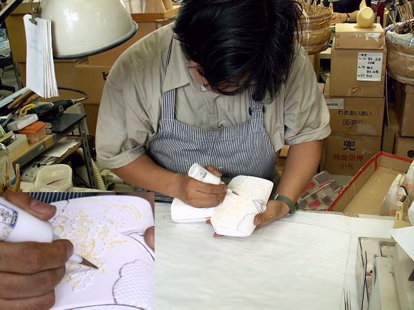 木目込み職人が木目込みの衣装にモデリング剤で絵付けをしているところ。金彩の工程のひとつ