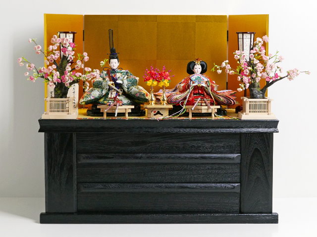 華やかな鳳凰の刺繍が特徴の雛人形を金屏風と黒塗り台に並べる収納飾り