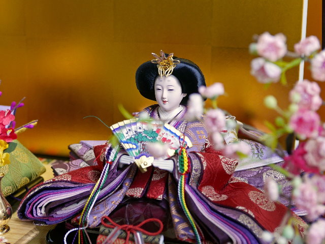 古典的な文様、丸の鶴を衣装に織り込んだ雛人形を金屏風と黒塗り台に並べる収納飾り
