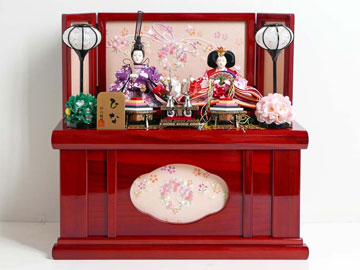 花柄で華やかな色彩の衣装の人形をコンパクトな赤色の収納箱に並べた雛人形です。