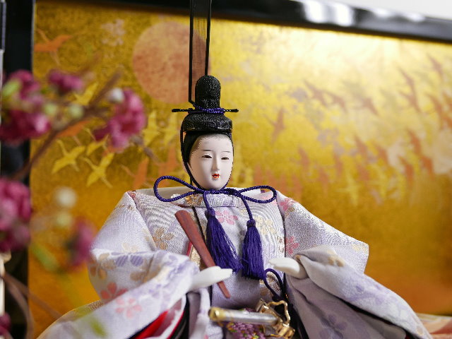 淡くきれいな色合いの雛人形を鶴の金屏風と黒塗り台に並べる収納飾り