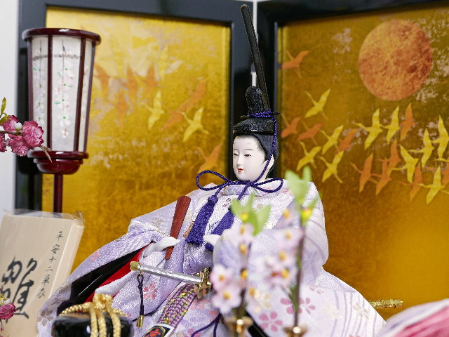 淡くきれいな色合いの雛人形を鶴の金屏風と黒塗り台に並べる収納飾り