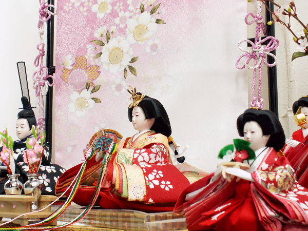 桜柄友禅衣装の赤いおひな様を几帳の前で官女と一緒に飾った雛人形五人飾り