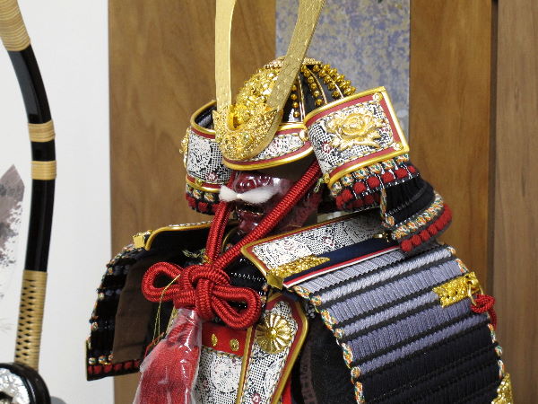 黒い小札を黒糸で威した渋めのコンパクト大鎧を箔散らし桜絵で飾る五月人形