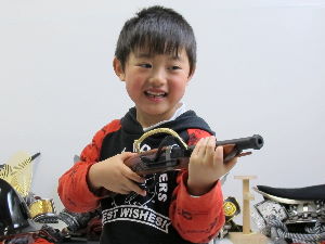 短い火縄銃の模造品を手にして喜ぶ男の子