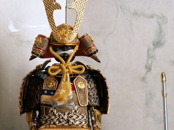 金色の小札を緋糸で威した豪華で品の良いコンパクト7号大鎧をすっきりとした二曲屏風で飾る五月人形