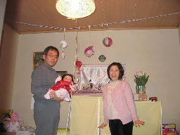雛人形の前で雛祭りを迎える赤ちゃんを抱っこしたお母さんと横に並んだお父さんの記念写真